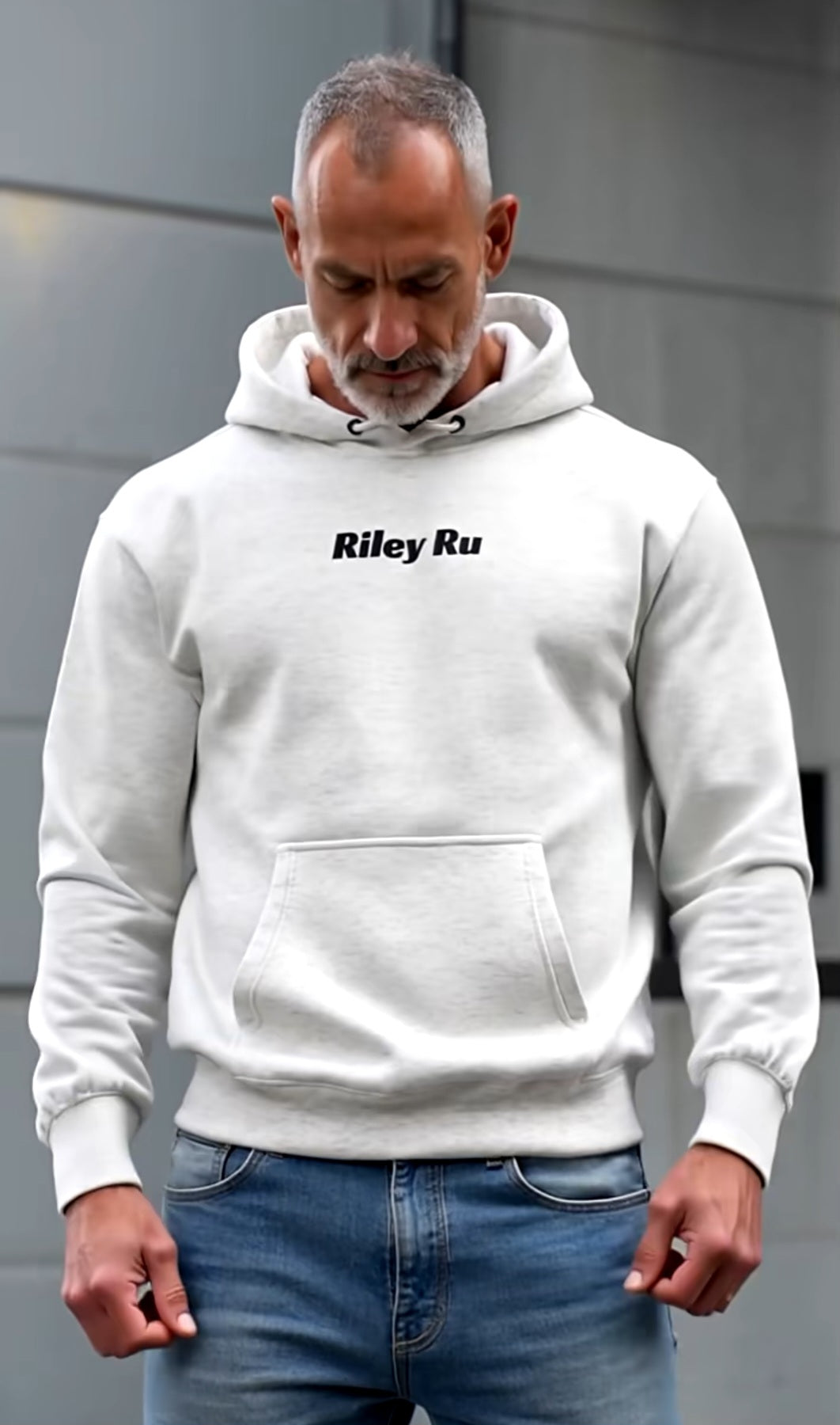 Man wearing a white hoodie with 'Riley Ru' text, standing against a gray background.