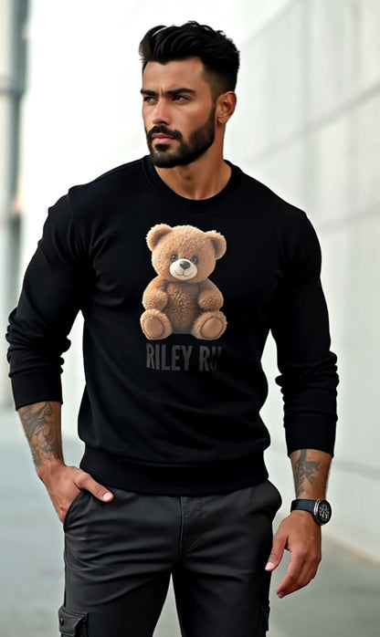Man wearing a black sweatshirt with a teddy bear graphic and text, standing against a blurred background.