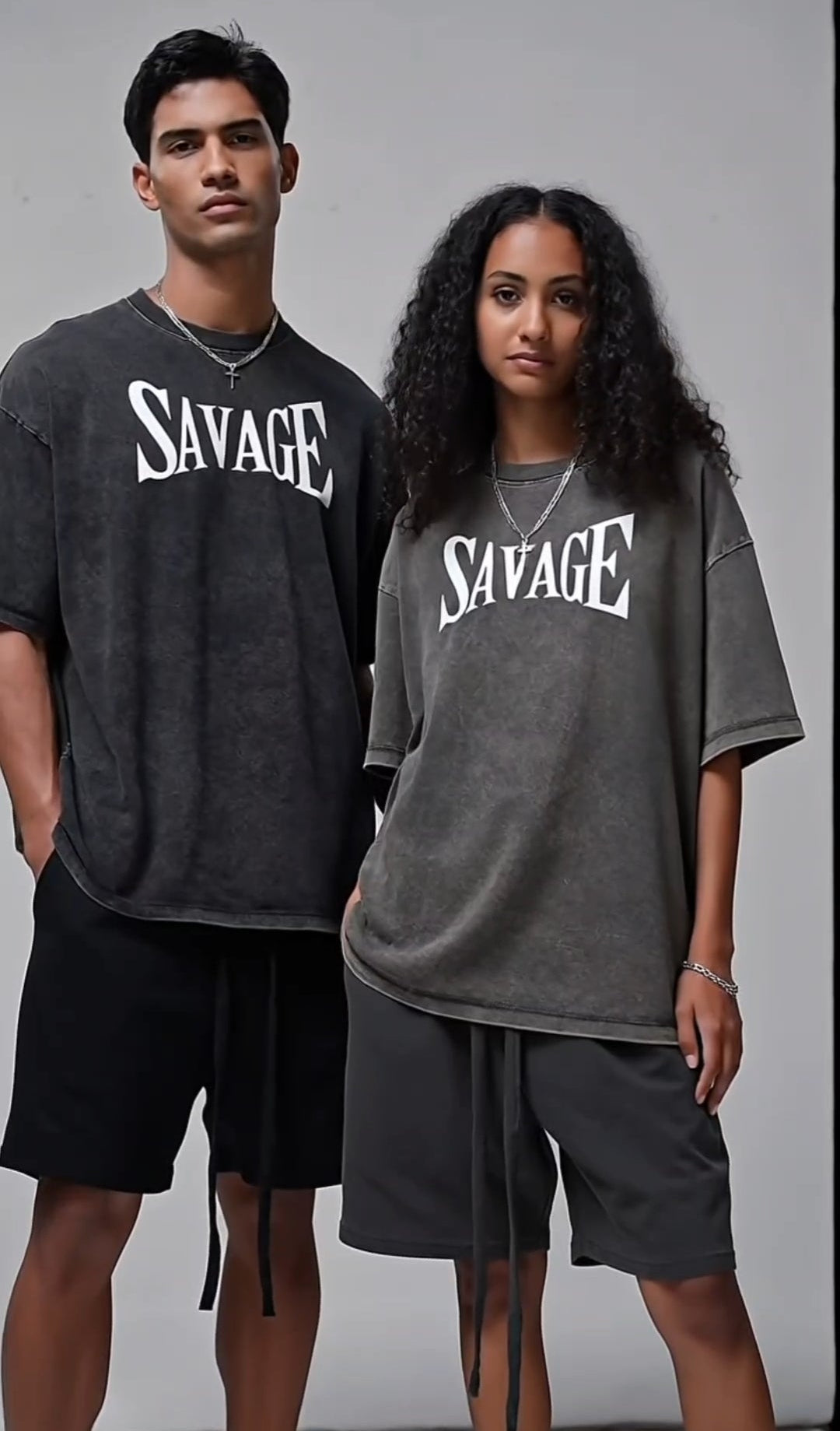 Two people wearing 'SAVAGE' t-shirts on a plain background