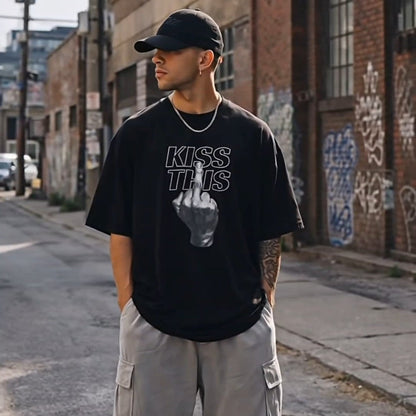 Person wearing a black t-shirt with text and graphics, gray cargo pants, and black sneakers on an urban street.