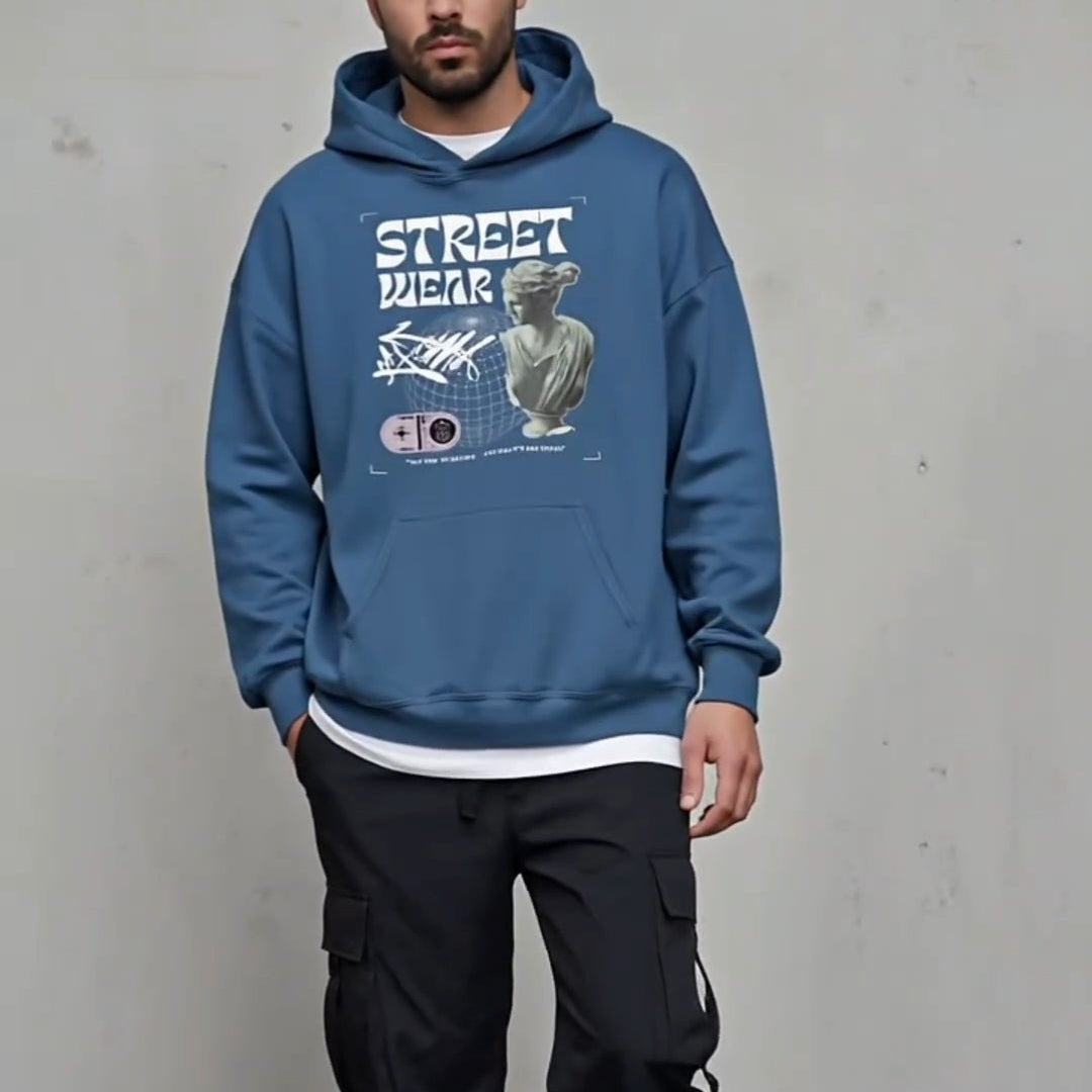 Man wearing a blue hoodie with graphic design against a plain background