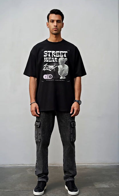 Person wearing a black t-shirt with text and graphics, standing against a plain background