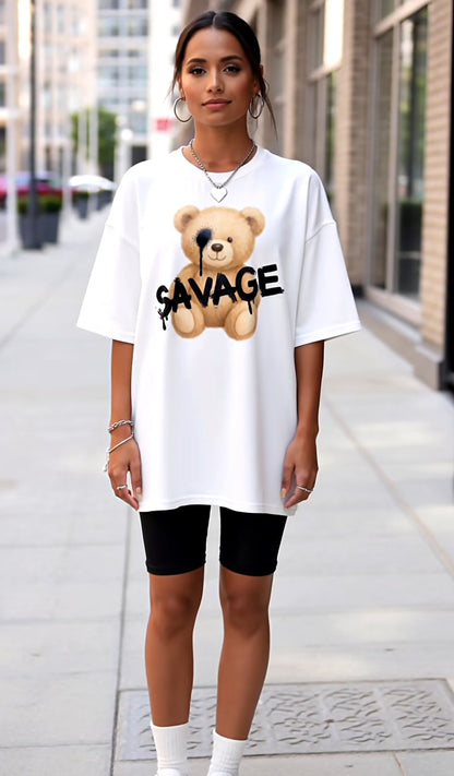 Person wearing a white oversized t-shirt with a bear graphic and 'SAVAGE' text on a city street.