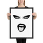 Person holding a framed artwork of a stylized face with black eyes and lips on a white background