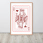 Framed playing card print of a queen with hearts on a white wall.