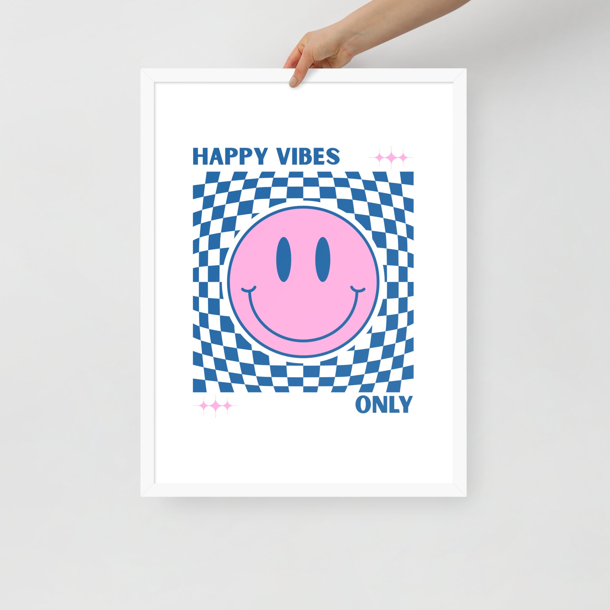 Framed poster with a pink smiley face and blue checkered pattern, text 'Happy Vibes Only' on a white background.