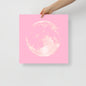 Hand holding a pink card with a white circular design on a light gray background