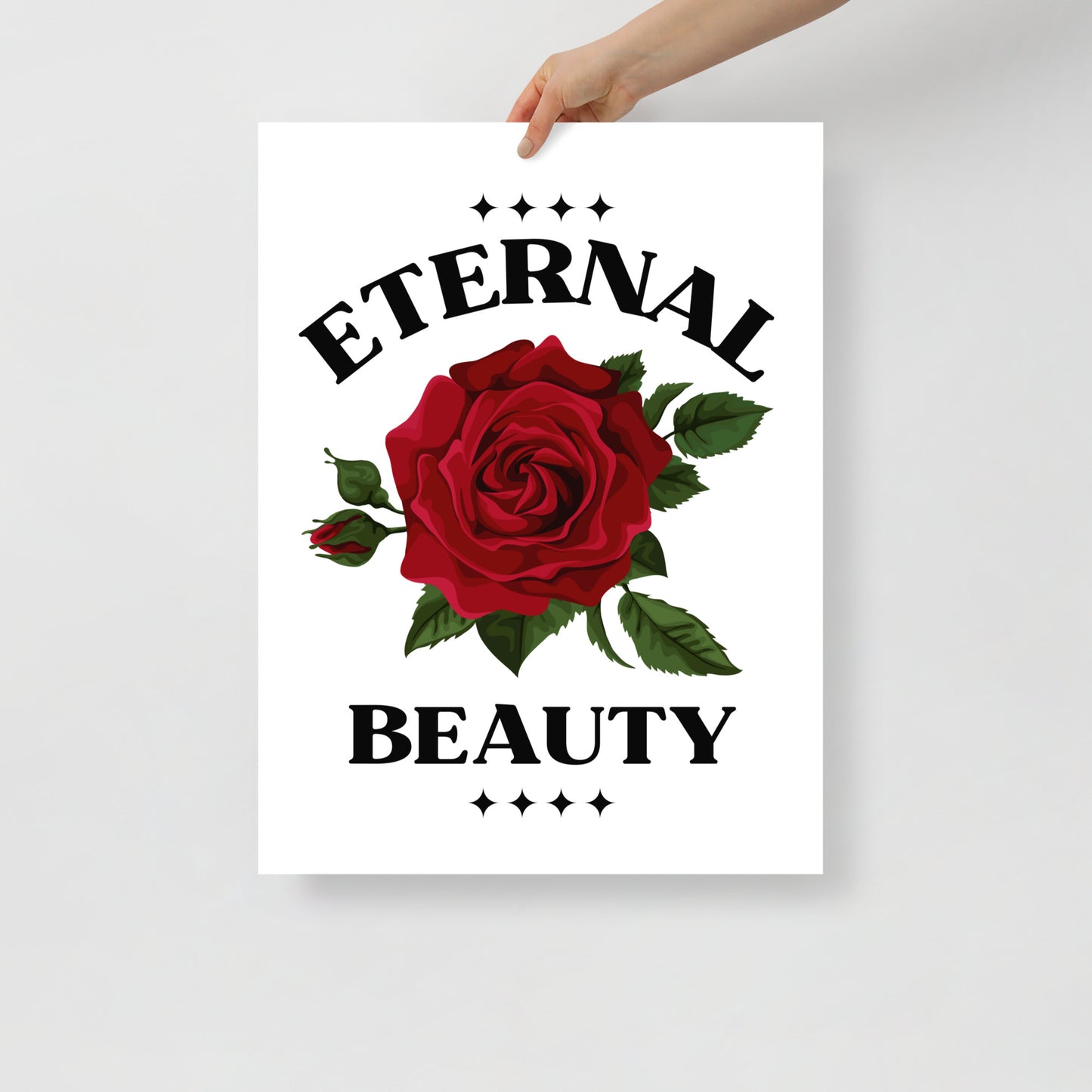 Poster with a red rose and 'Eternal Beauty' text held by a hand on a light gray background