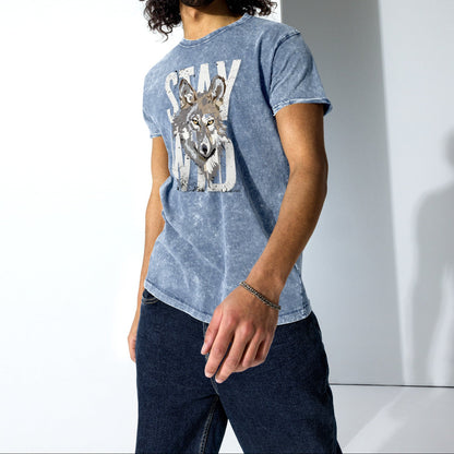 Man wearing a blue graphic t-shirt with a wolf design against a white background