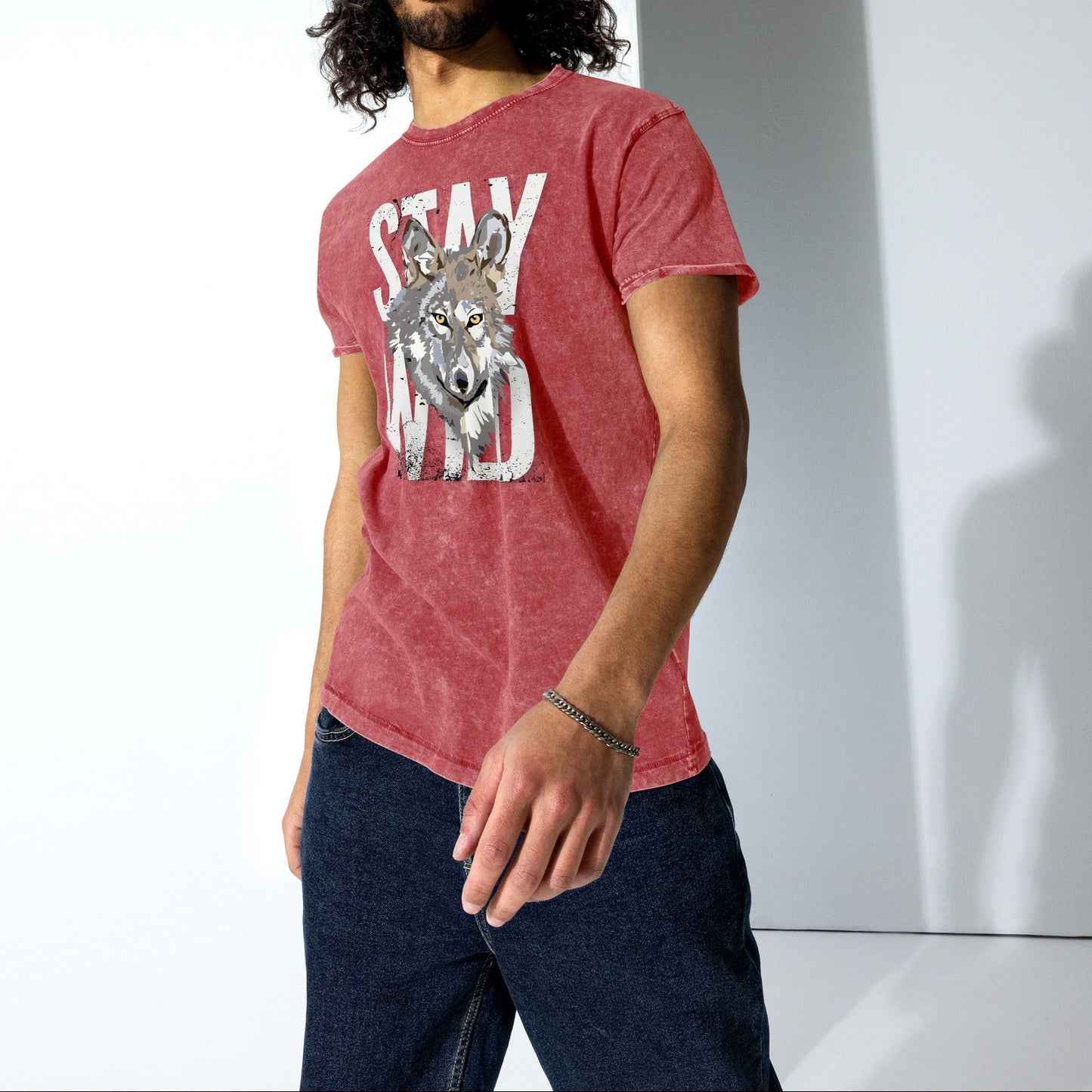 Man wearing a red t-shirt with a graphic design and text, standing against a white wall.