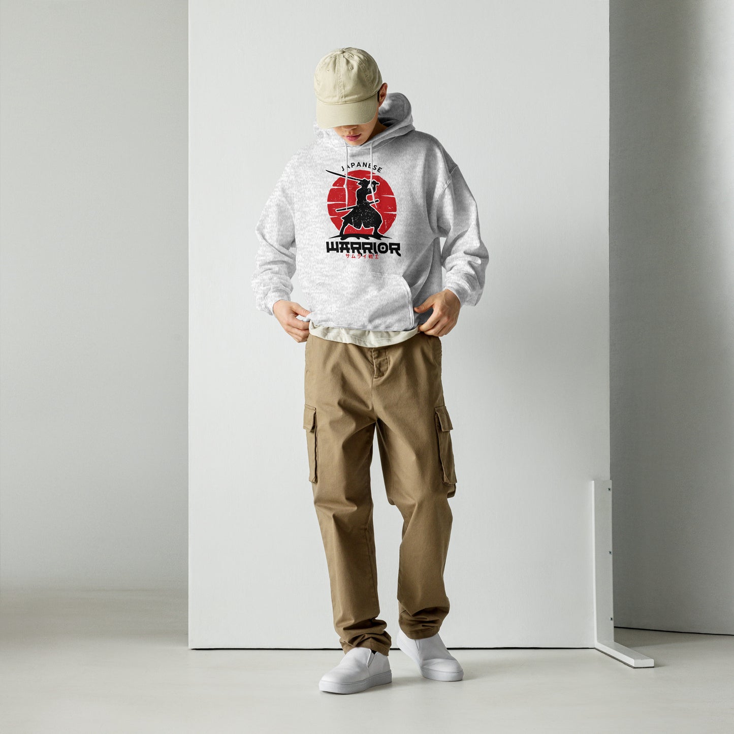 Person wearing a white hoodie with a graphic design and brown cargo pants on a plain background