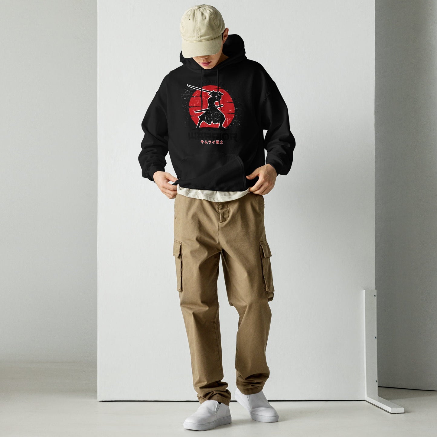 Person wearing a black hoodie with 'SLONVE' text, beige cap, and cargo pants against a white background