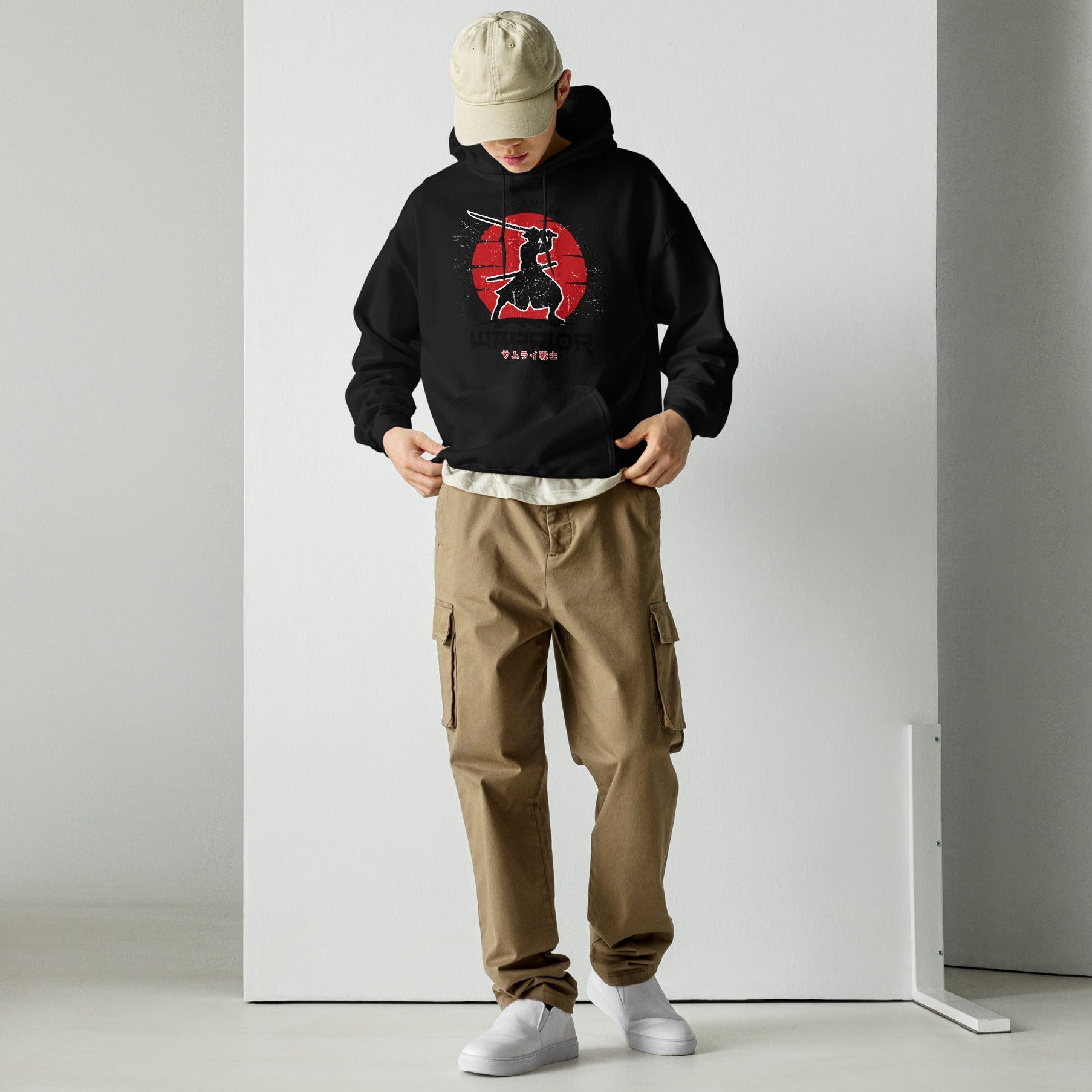 Person wearing a black hoodie with 'SLONVE' text, beige cap, and cargo pants against a white background