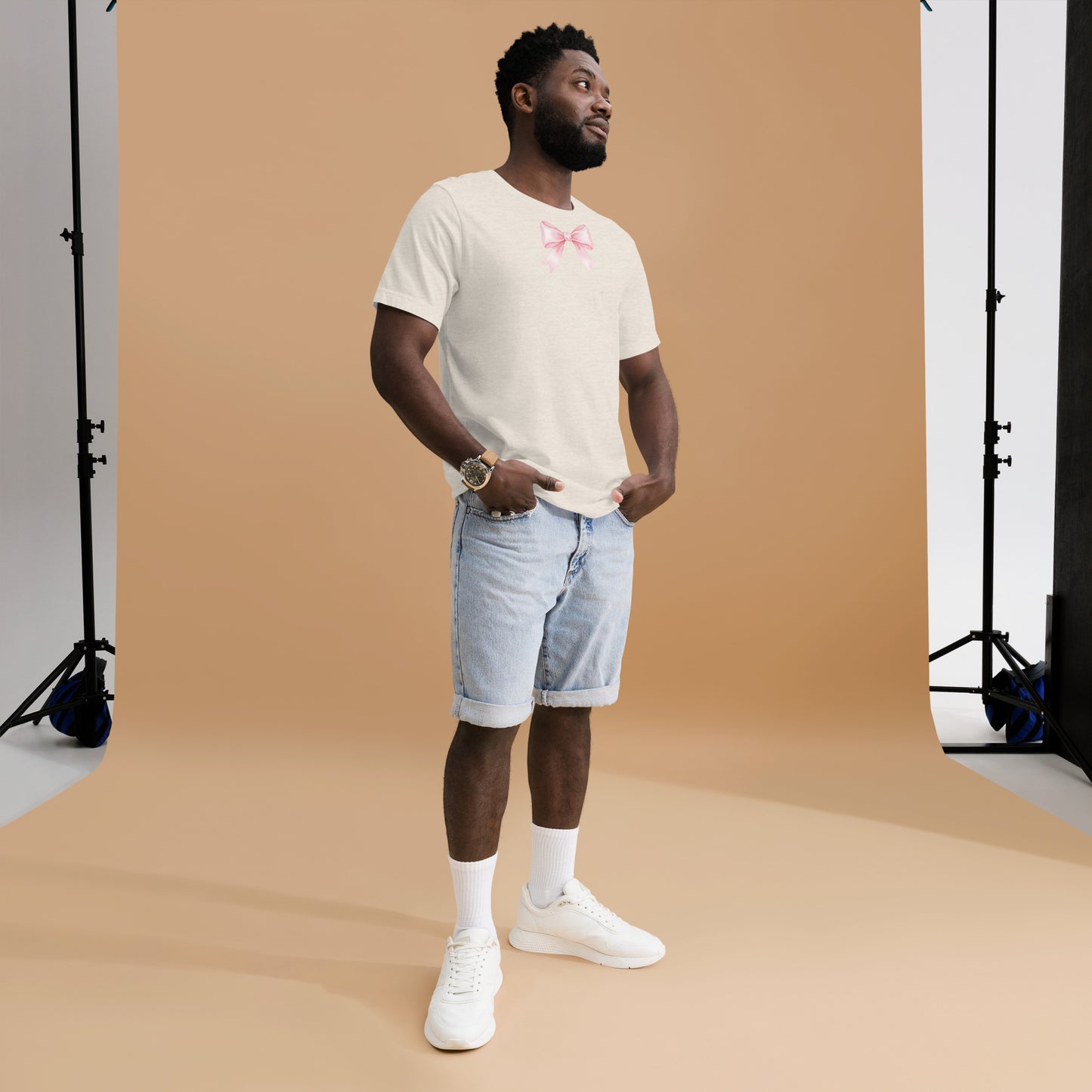 Man wearing a white t-shirt with text and light blue shorts standing against a brown backdrop