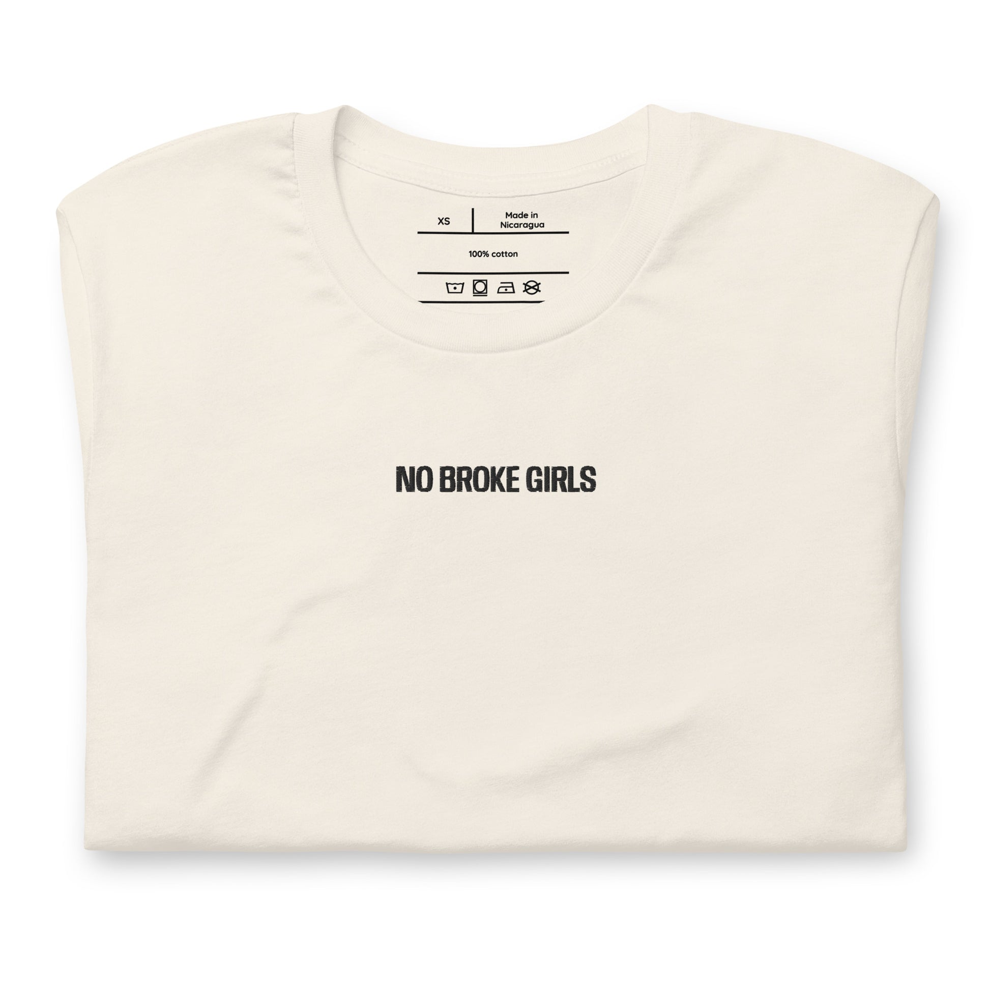 Folded cream t-shirt with 'NO BROKE GIRLS' text on a white background